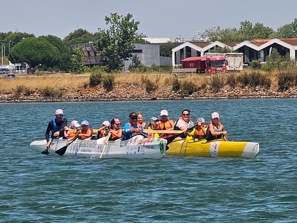 Une pirogue V6 complète, enfants et adultes en gilet, lors d'une séance découverte